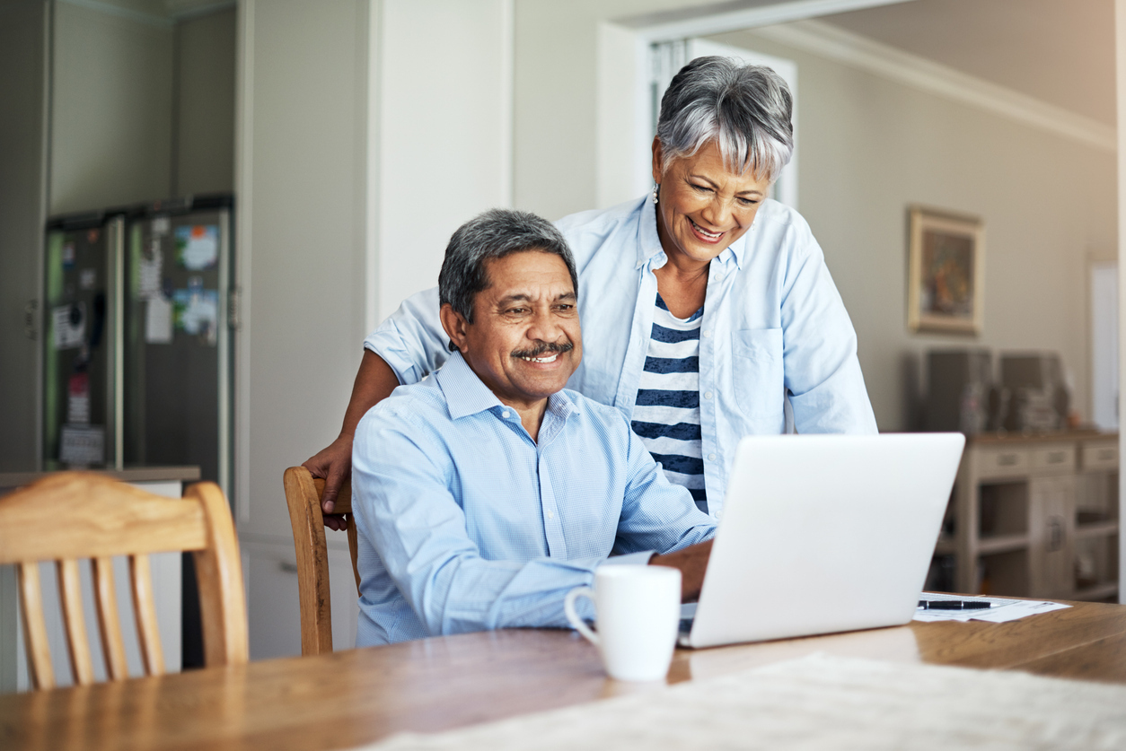 Older couple of color reviewing financial plans together on a laptop, representing wealth empowerment and financial literacy.